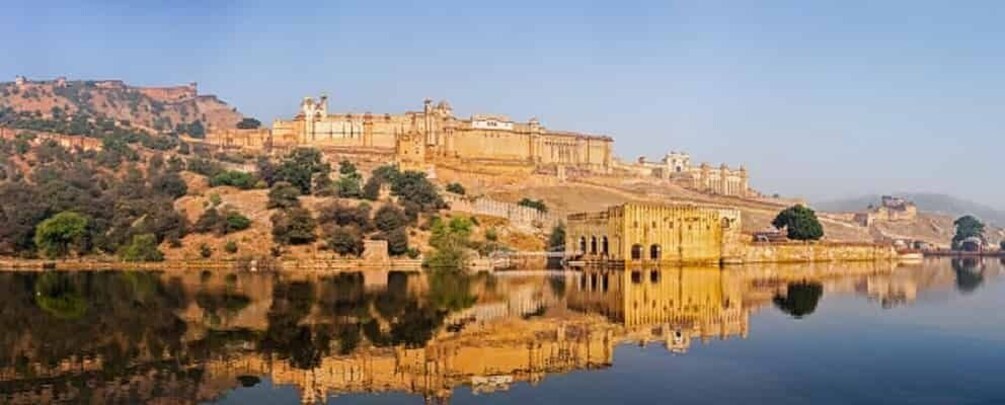 A historic fort on a hill overlooking a calm lake with clear reflections. 1