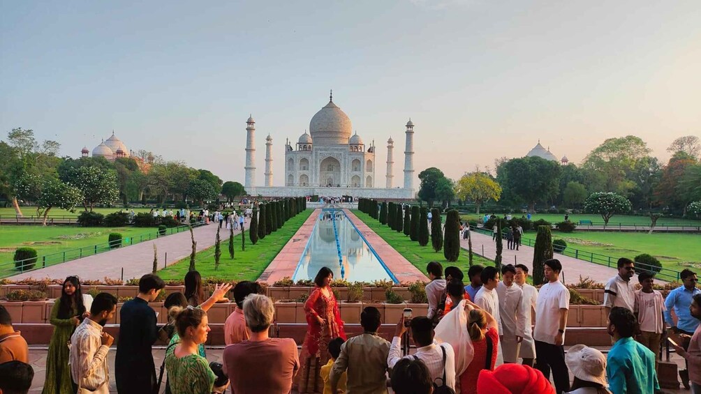 The Taj Mahal with a reflection pool in the foreground and visitors around. 2