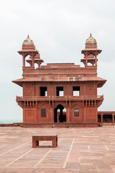 A large, red sandstone building with two domes and a central archway. 3