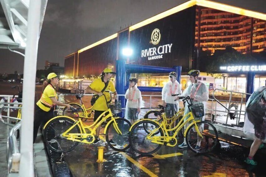 A group of people with bicycles in front of a building with 'River City Bangkok' signage. 4