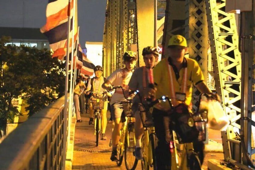 Cyclists on a bridge with flags and structural beams. 2