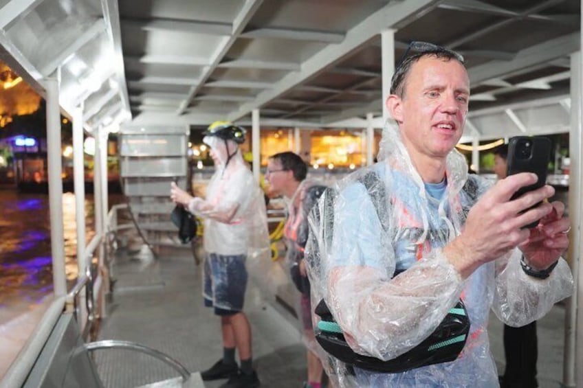 People in rain gear on a covered walkway, holding phones. 5
