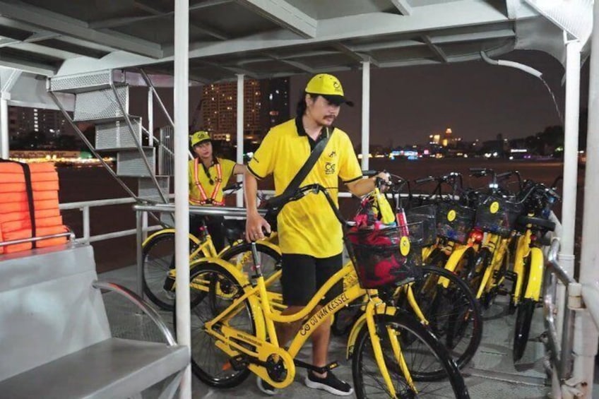 A person standing next to a yellow bicycle with a basket, in an outdoor setting with a railing and a staircase. 3