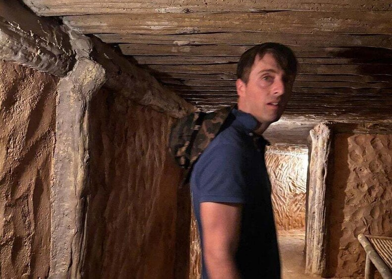 A person in a rustic, wooden interior with rough stone walls and a wooden ceiling. 3