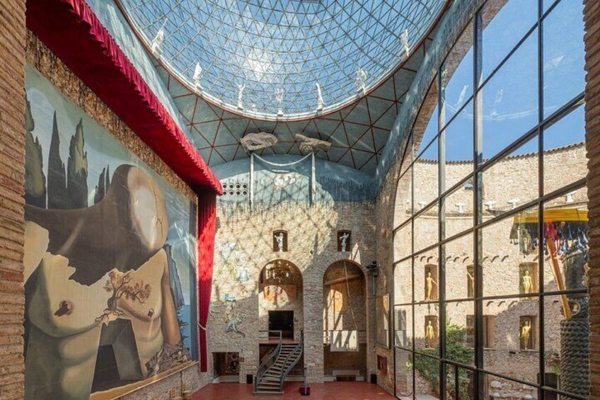A spacious interior with a high ceiling, a large mural, and a glass dome. 4