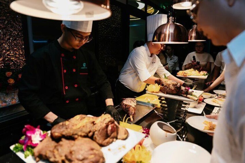 Chefs preparing food in a kitchen with a focus on roasted meats and vegetables. 3