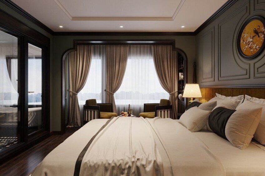 A hotel room with a large bed, two chairs, a desk, and a view of the city. 4