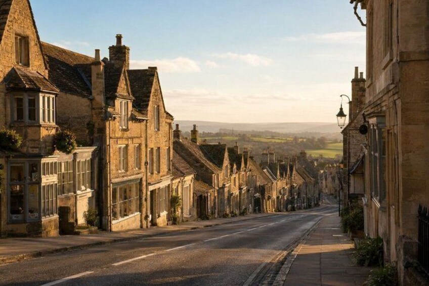 A historic street lined with traditional stone buildings, a clear sky, and a distant view of the countryside. 3