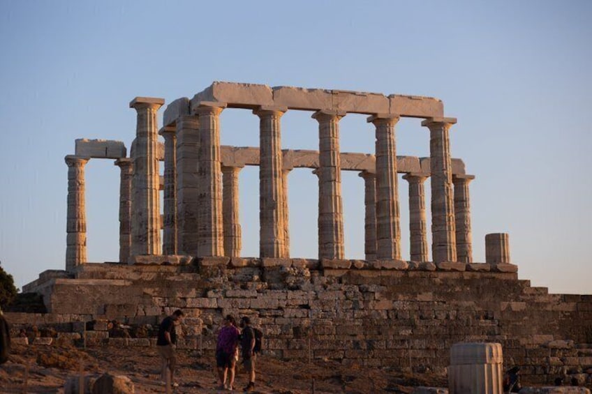 Ancient stone columns of a historical structure, with visitors nearby. 3
