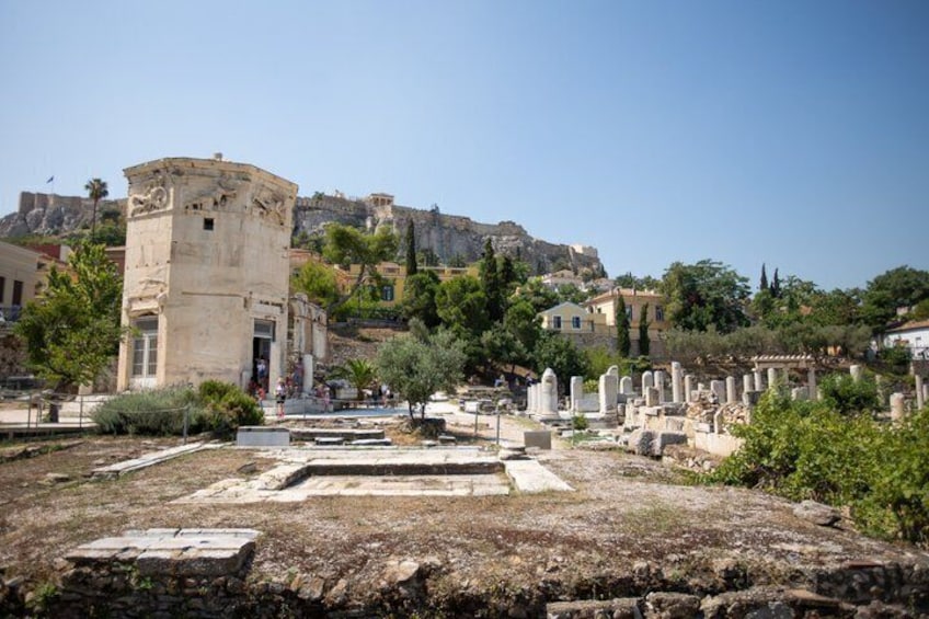 Ancient ruins with a prominent stone structure, scattered tombstones, and a backdrop of a hill with buildings. 2