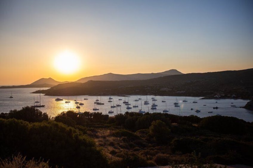 A coastal sunset with boats on the water and hills in the background. 4
