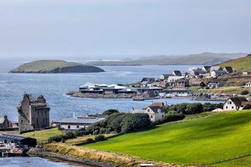 A coastal village with a prominent tower, houses, and a grassy hill. 1