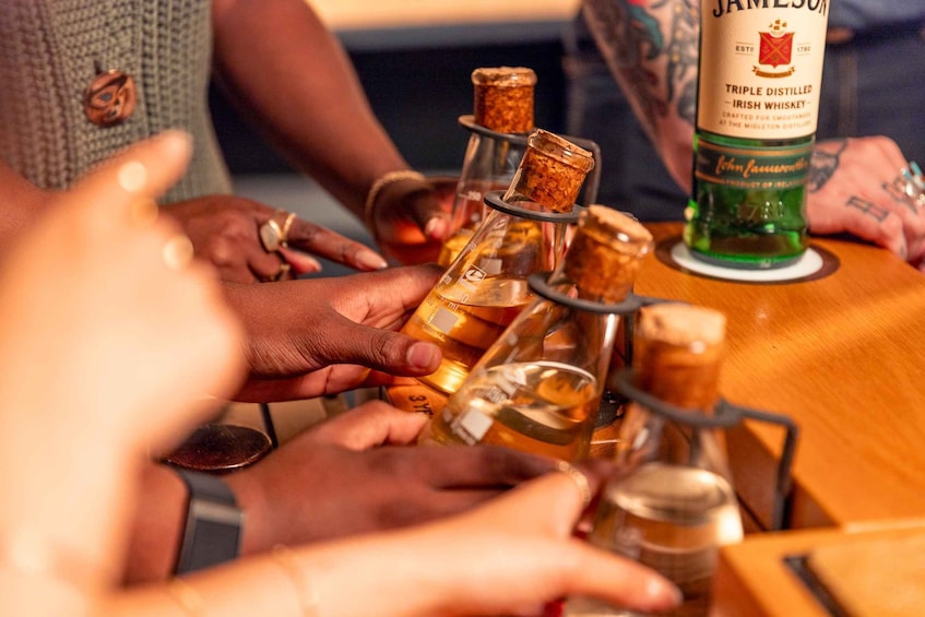 En gruppe mennesker holder og undersøger flasker med whisky. 5