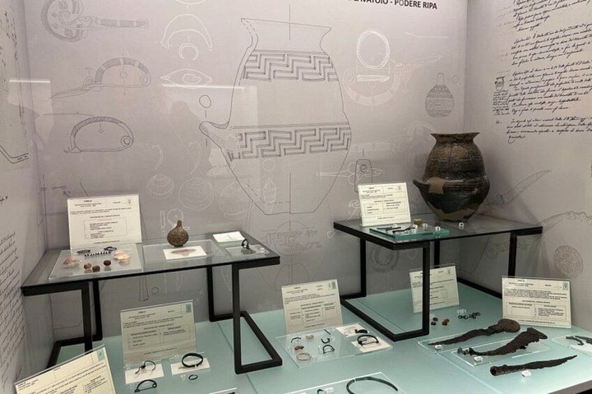 An exhibition with ancient artifacts, including pottery and jewelry, displayed on glass tables with informational labels. 5