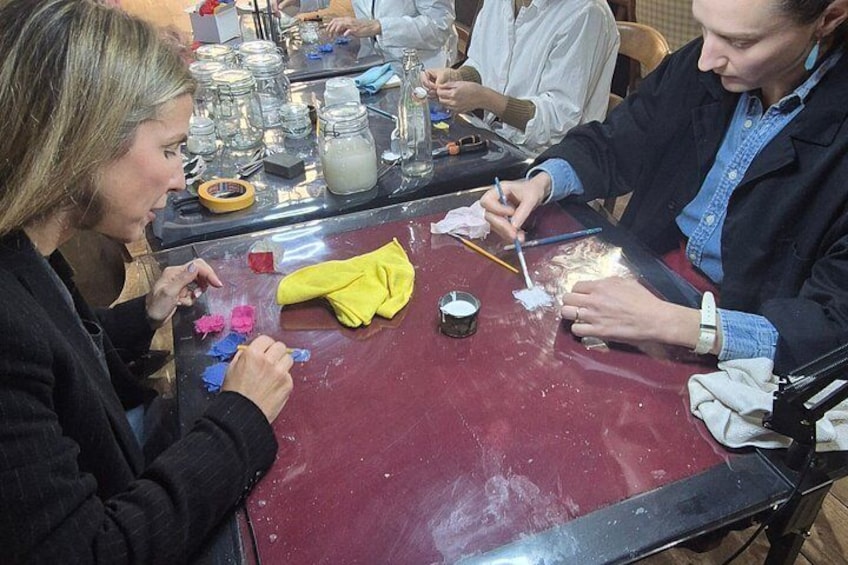 A group of people engaged in a craft activity at a table with various tools and materials. 2