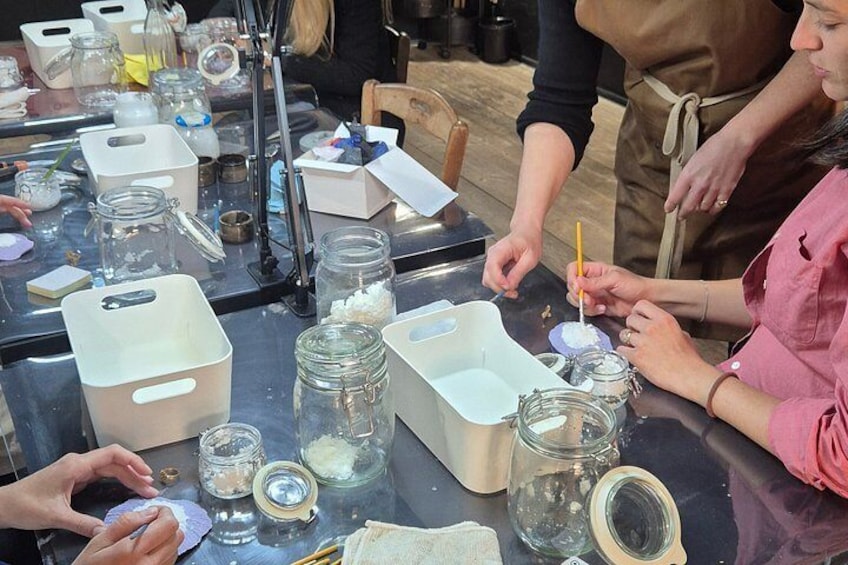 A group of people engaged in a craft activity, surrounded by jars, containers, and various crafting materials. 3