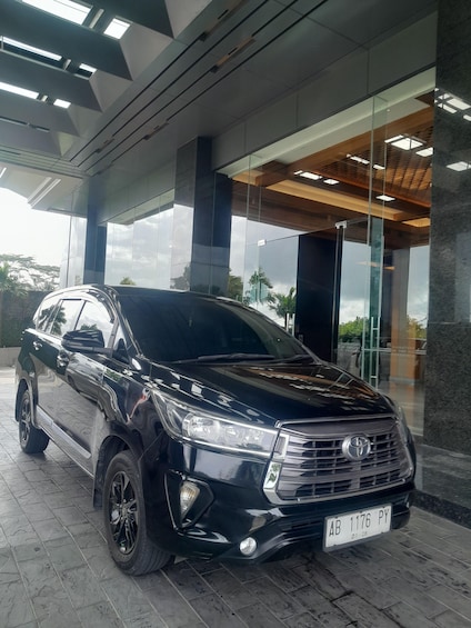 A black SUV parked in front of a modern building with large windows and a tiled floor. 2