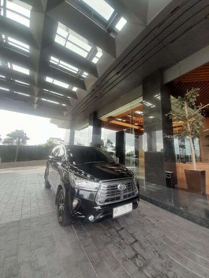 A black SUV parked in a modern building with a tiled floor and large windows. 3