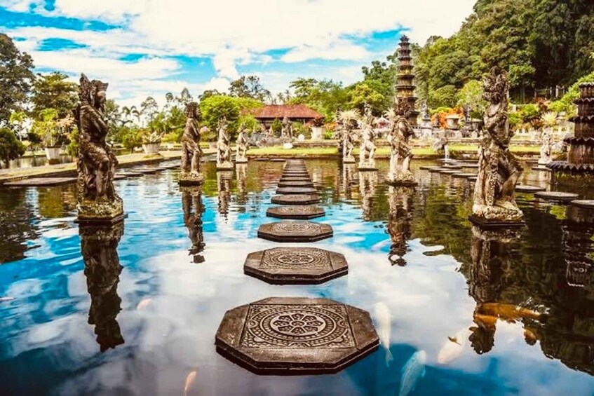 A tranquil waterway with stone steps leading to a pagoda, surrounded by statues and lush greenery. 1