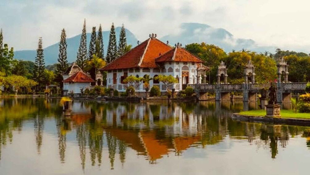 A traditional building with a red roof, surrounded by a calm lake and trees, with a mountain in the background. 5