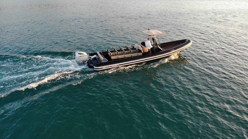 A motorboat with a canopy and seating, moving through calm waters. 3
