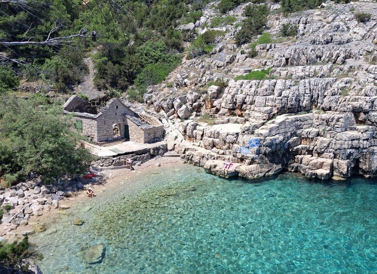 A coastal landscape with a small stone structure near the water's edge, surrounded by rocky terrain and sparse vegetation. 5