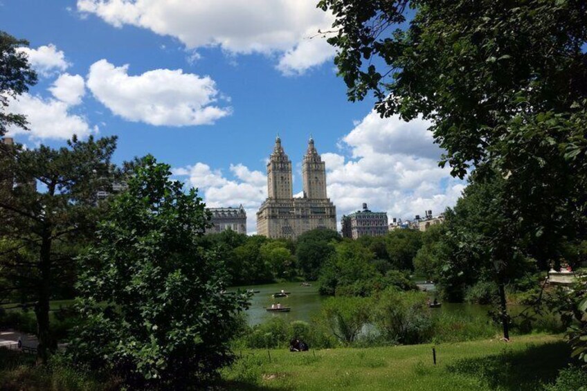 A park with a large building in the background, a pond, and trees. 4