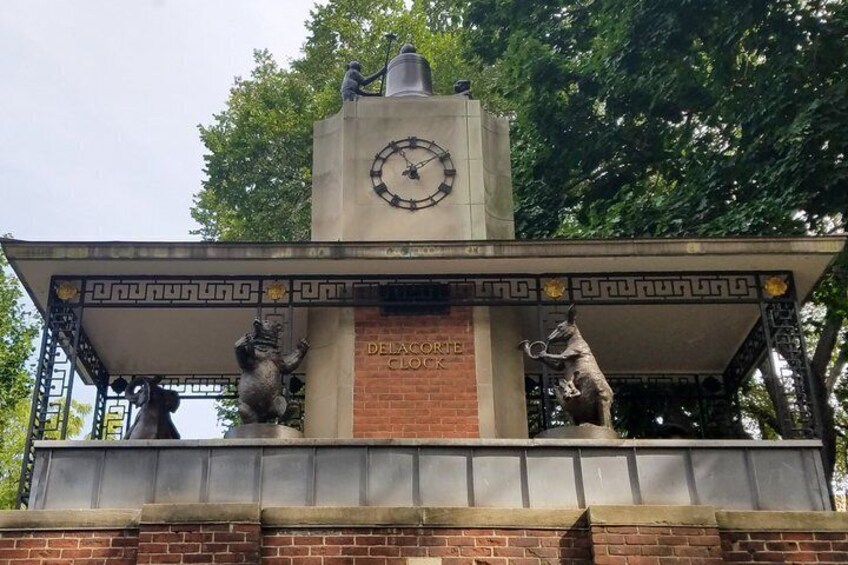 A clock tower with lions at its base and a plaque reading 'Delacroix Clock.' 1
