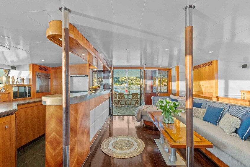 A modern kitchen with wooden cabinetry, a dining area with a table and chairs, and a view through large windows. 4