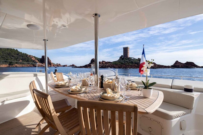 A table set for dining on a boat with a view of a rocky island and a flag. 5
