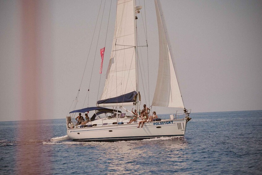A sailboat with the registration PO001GKT sailing on calm waters. 1