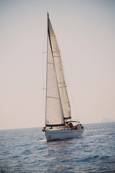 A sailboat with a single sail on a calm sea. 2