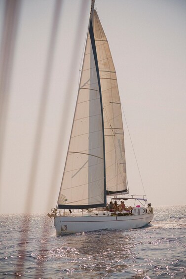A sailboat with a large sail on calm waters. 4