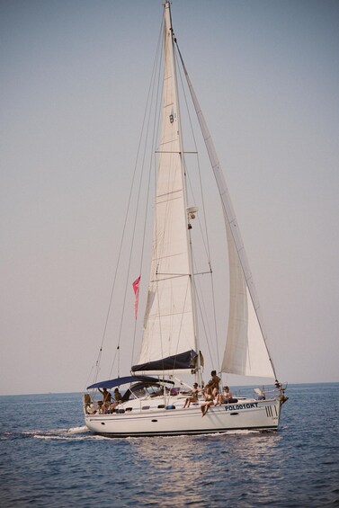A sailboat with people on deck, sailing on the water. 3