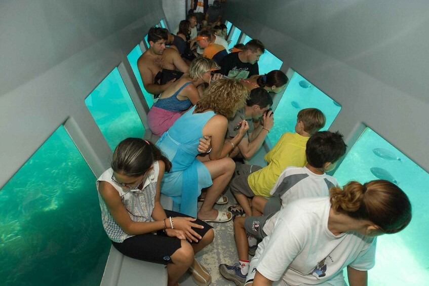 A group of people seated in a narrow, enclosed space with a blue-lit water feature. 4