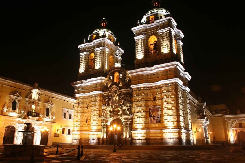 A historic building with two prominent towers, ornate facades, and a central entrance. 1