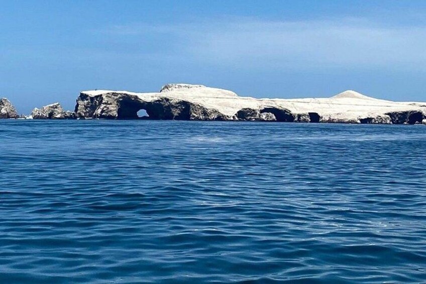 A glacier with a cave opening, surrounded by water. 3