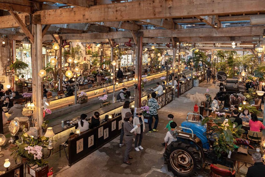 An indoor market with wooden beams, hanging lights, and various stalls. 1