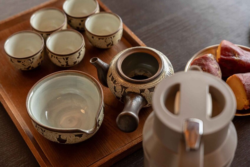 A tray with tea cups and a teapot, accompanied by sweet potatoes. 5