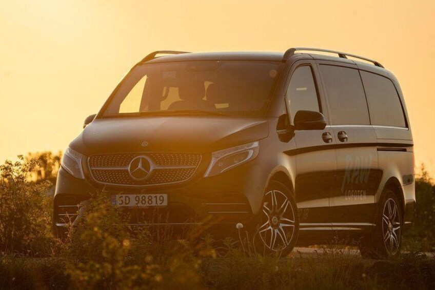 A Mercedes-Benz SUV parked in a field with a sunset in the background. 5