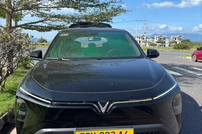 A black car parked on a street with houses in the background. 5