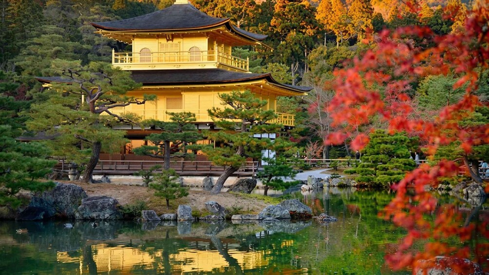 A traditional Japanese pagoda with a reflection in a pond, surrounded by autumn foliage and rocks. 5
