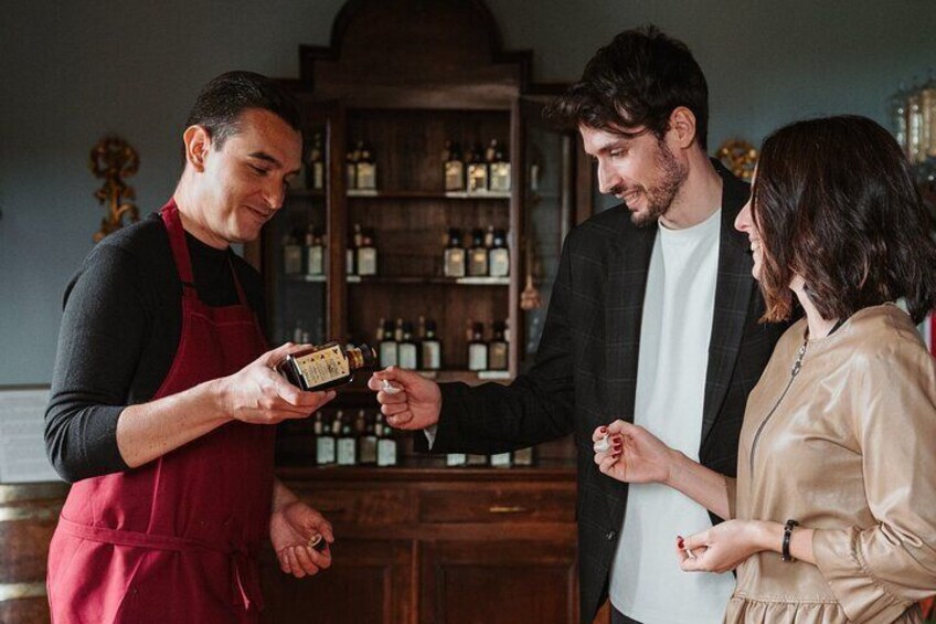 A person in a red apron holding a bottle, interacting with two others in a bar setting. 2