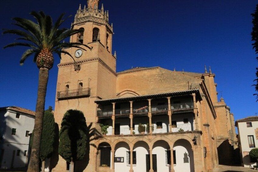 Una chiesa storica con un campanile, finestre ad arco e una palma sullo sfondo. 2