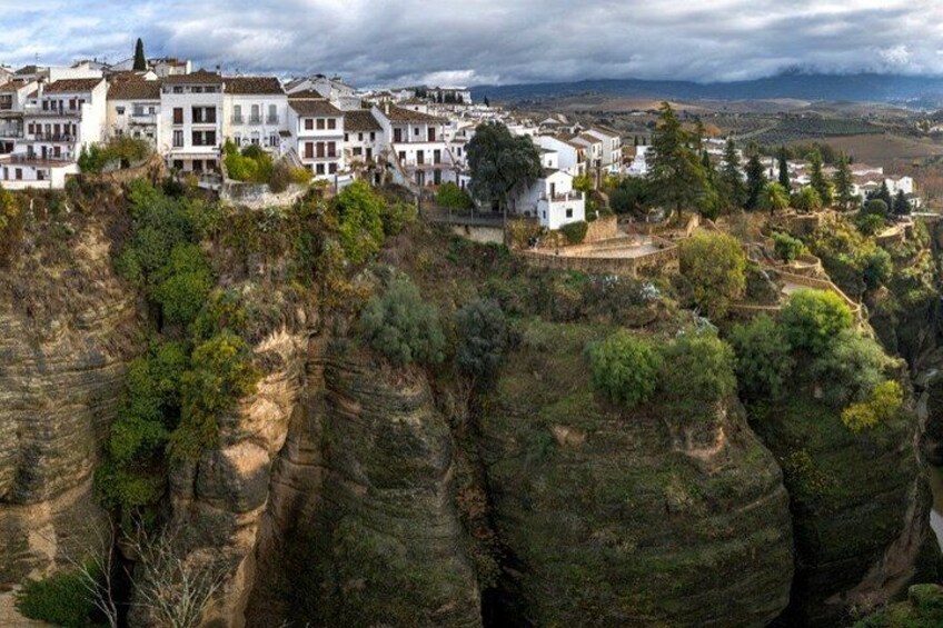 Una località costiera con edifici bianchi arroccati su scogliere, circondata da un terreno roccioso e vegetazione. 1