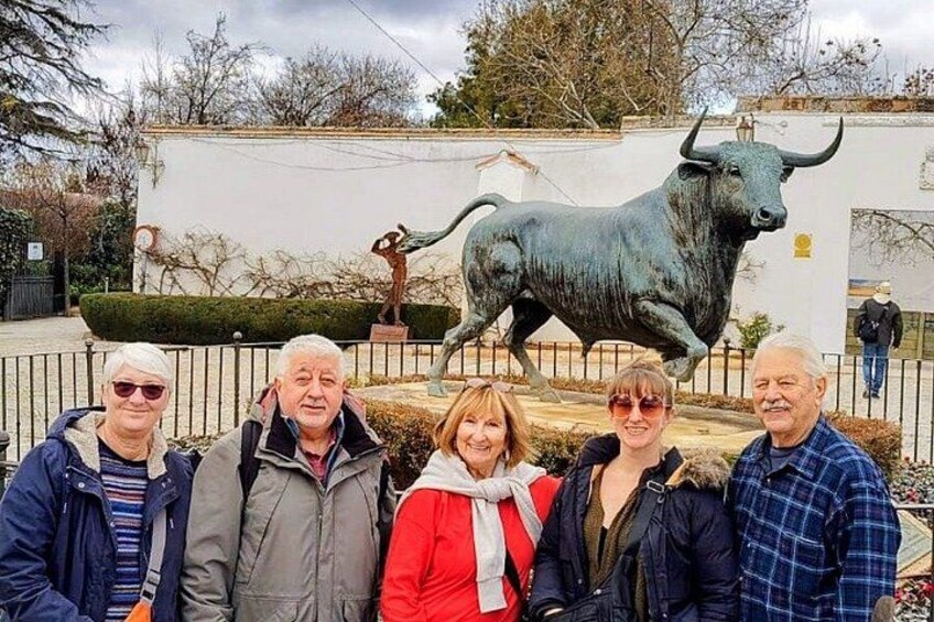 Un gruppo di persone che posa davanti a una statua di toro e a un edificio. 4