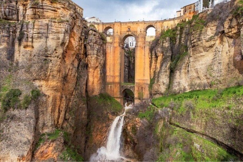 Una cascata che si getta in una gola, con un ponte storico sullo sfondo. 3