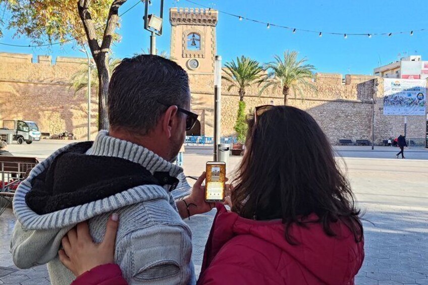 A couple taking a photo with a historic tower in the background. 1