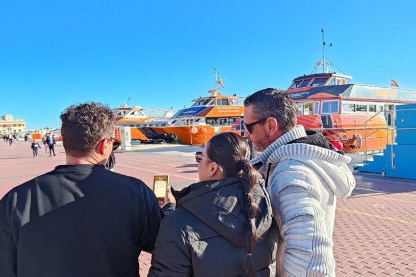 A group of people taking a selfie with a boat in the background. 3