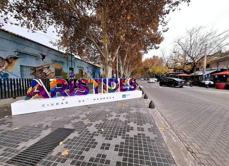 A street sign for 'ARISTIDES' with a colorful mural in the background. 2